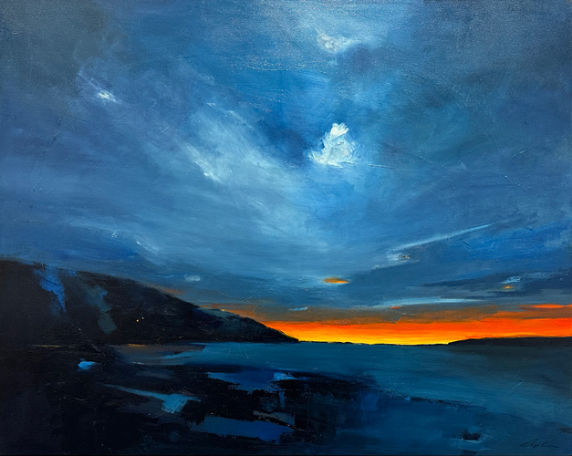 Deep blue sea and a dark headland sit beneath turbulent blue-grey clouds, with a narrow, brilliant orange sunset at the horizon.